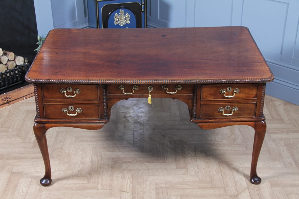 A Georgian mahogany writing desk featuring a rectangular top, central kneehole drawer flanked by side drawers, polished brass handles, and cabriole legs ending in pad feet. View XII
