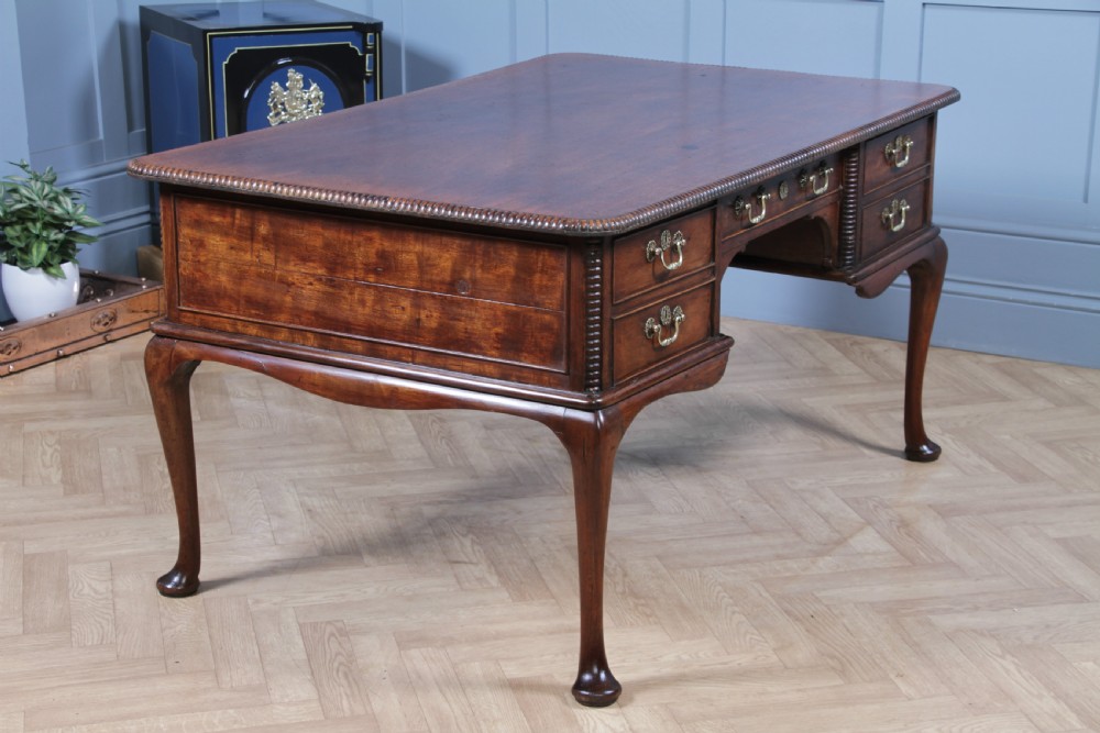 A Georgian mahogany writing desk featuring a rectangular top, central kneehole drawer flanked by side drawers, polished brass handles, and cabriole legs ending in pad feet. View XV