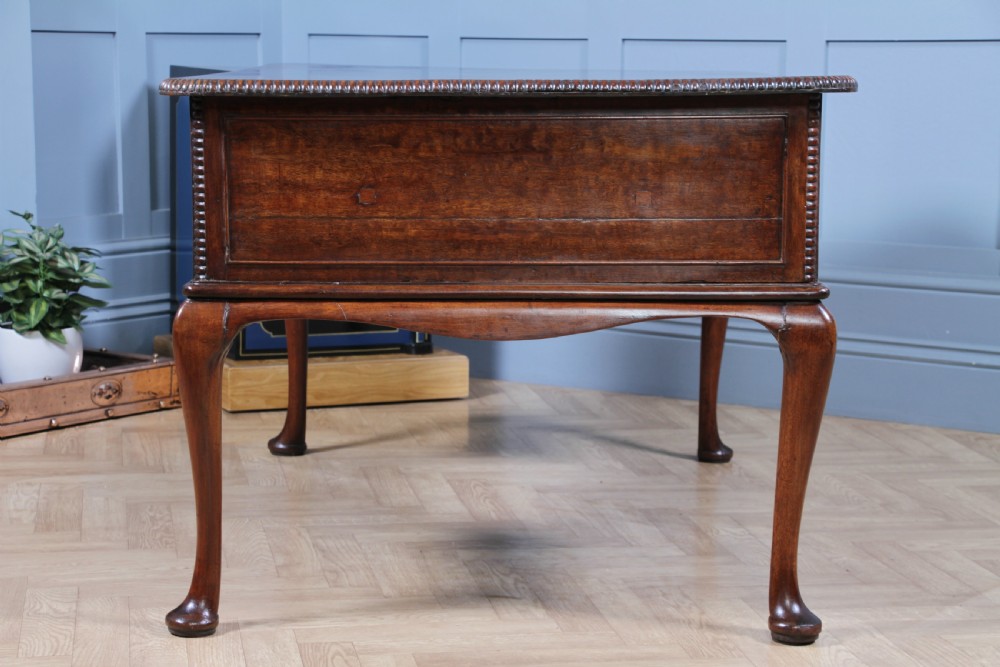 A Georgian mahogany writing desk featuring a rectangular top, central kneehole drawer flanked by side drawers, polished brass handles, and cabriole legs ending in pad feet. View XVI
