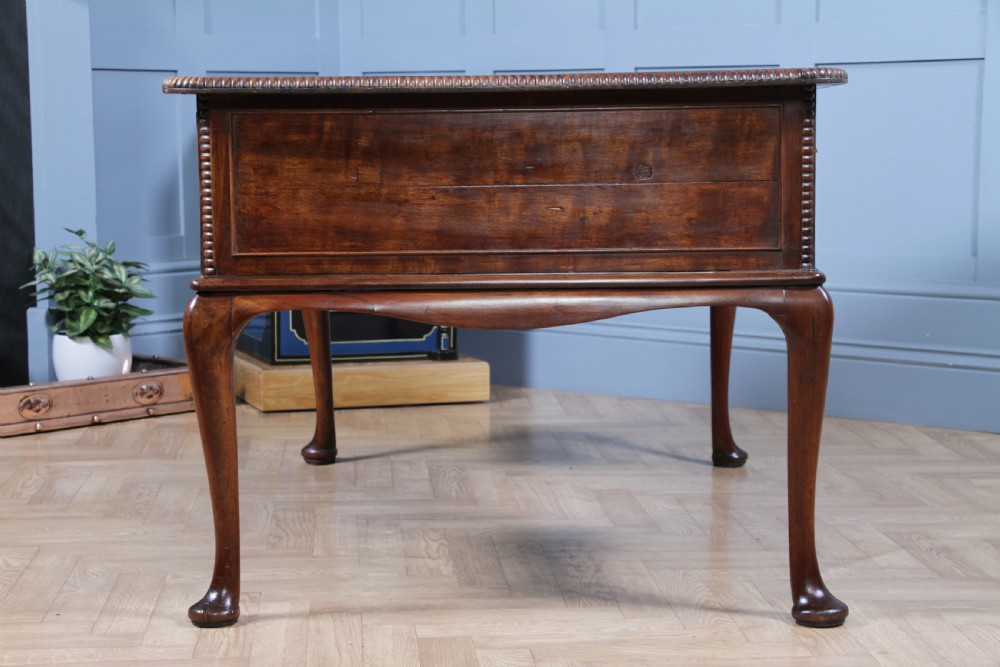 A Georgian mahogany writing desk featuring a rectangular top, central kneehole drawer flanked by side drawers, polished brass handles, and cabriole legs ending in pad feet. View XVII