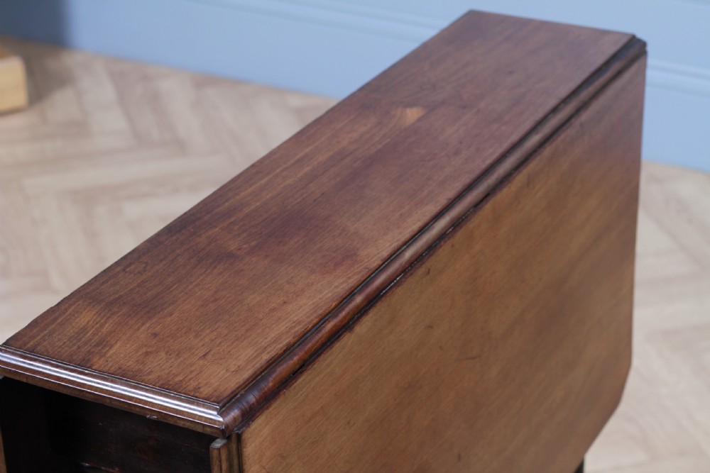 An Edwardian solid mahogany Sutherland table shown folded with turned legs, a lower stretcher bar, and small castors. View VII