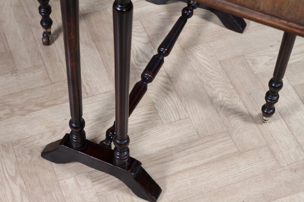 An Edwardian solid mahogany Sutherland table shown folded with turned legs, a lower stretcher bar, and small castors. View IX