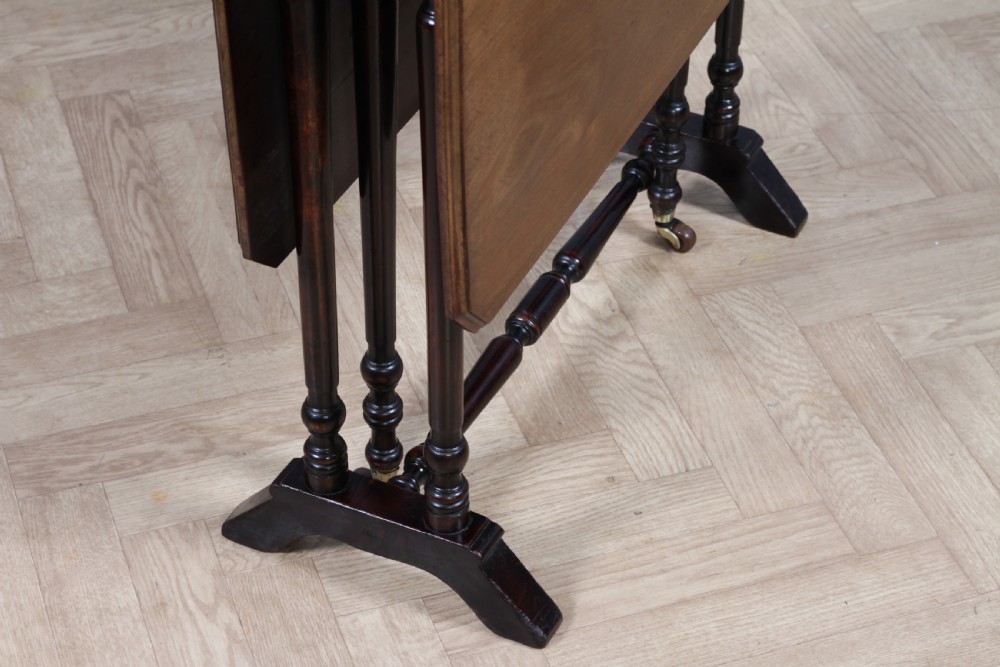 An Edwardian solid mahogany Sutherland table shown folded with turned legs, a lower stretcher bar, and small castors. View XI