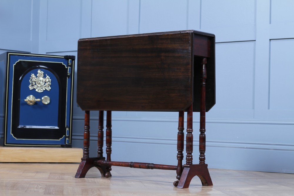 An Edwardian solid mahogany Sutherland table with folded drop-leaf sides, turned spindle legs, and ceramic castors on trestle feet. View IX