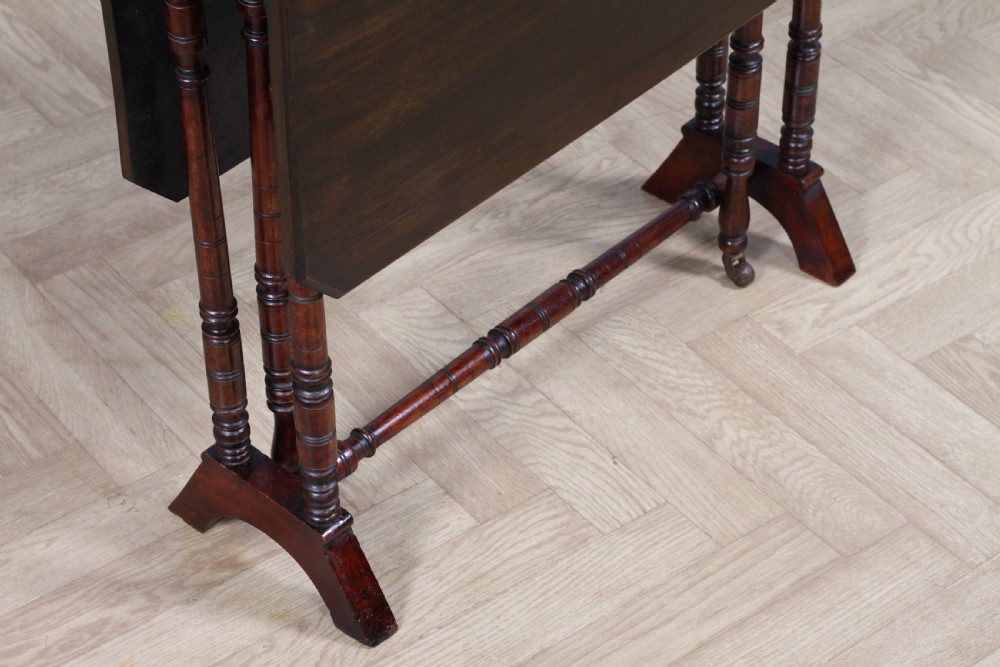 An Edwardian solid mahogany Sutherland table with folded drop-leaf sides, turned spindle legs, and ceramic castors on trestle feet. View XIII