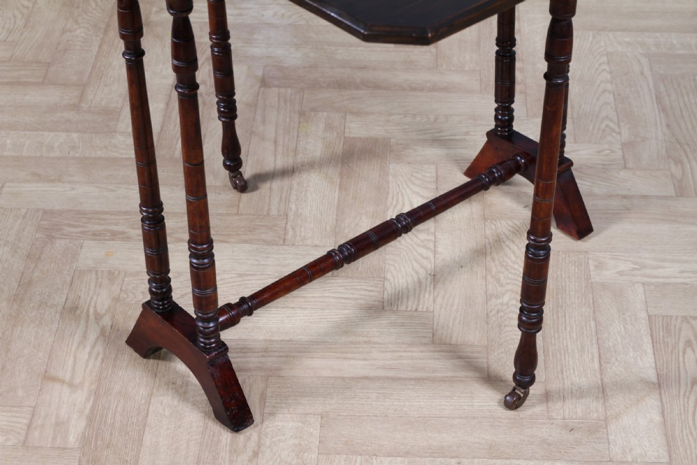 An Edwardian solid mahogany Sutherland table with folded drop-leaf sides, turned spindle legs, and ceramic castors on trestle feet. View XIV