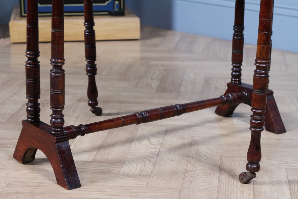 An Edwardian solid mahogany Sutherland table with folded drop-leaf sides, turned spindle legs, and ceramic castors on trestle feet. View XVII