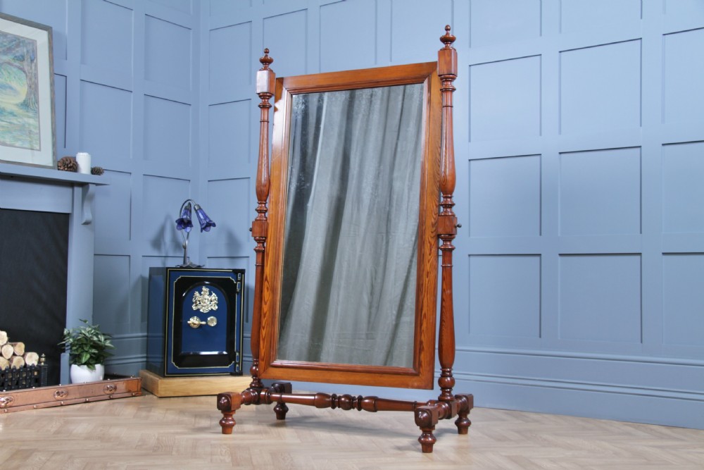 Victorian pitch pine cheval mirror featuring turned upright pillars, decorative finials, and a large tilting glass plate.
