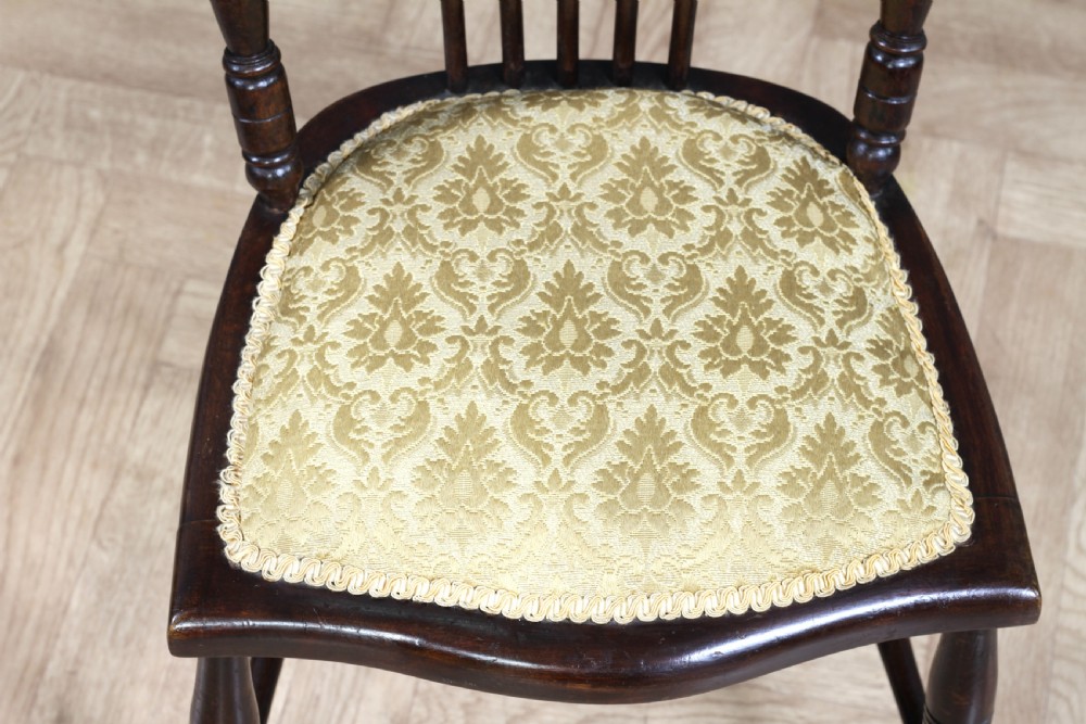 An Edwardian dark walnut nursing chair featuring a spindled stick back, turned legs, and a patterned yellow fabric seat. View III