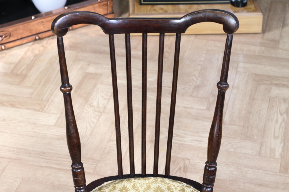 An Edwardian dark walnut nursing chair featuring a spindled stick back, turned legs, and a patterned yellow fabric seat. View IV