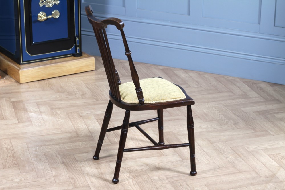 An Edwardian dark walnut nursing chair featuring a spindled stick back, turned legs, and a patterned yellow fabric seat. View VII