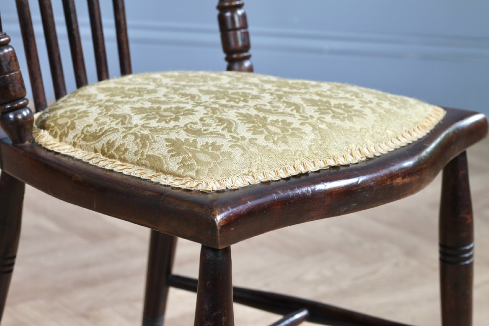 An Edwardian dark walnut nursing chair featuring a spindled stick back, turned legs, and a patterned yellow fabric seat. View IX