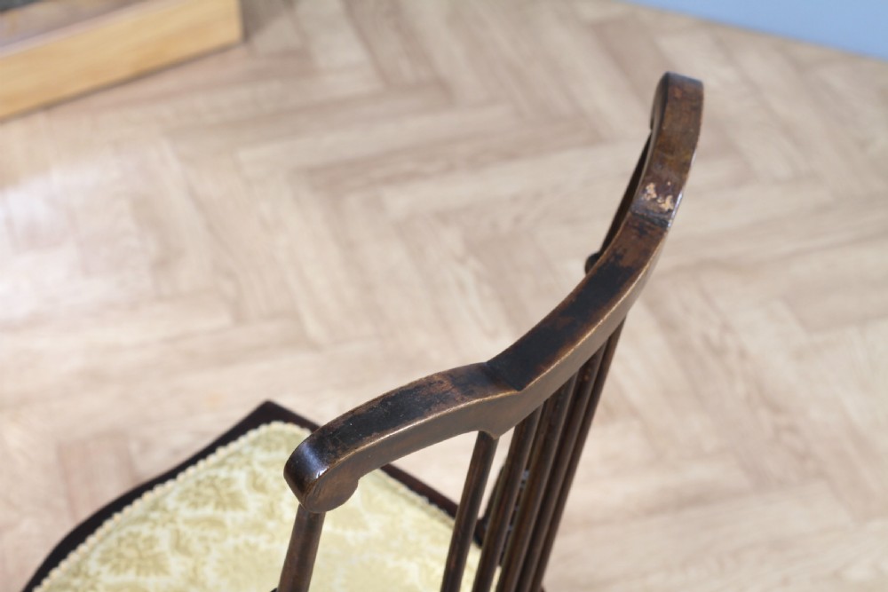 An Edwardian dark walnut nursing chair featuring a spindled stick back, turned legs, and a patterned yellow fabric seat. View X