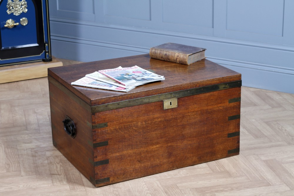An open Victorian oak campaign trunk featuring brass-bound corners, a central brass keyhole escutcheon, and a fitted interior lined in deep red velvet. View II