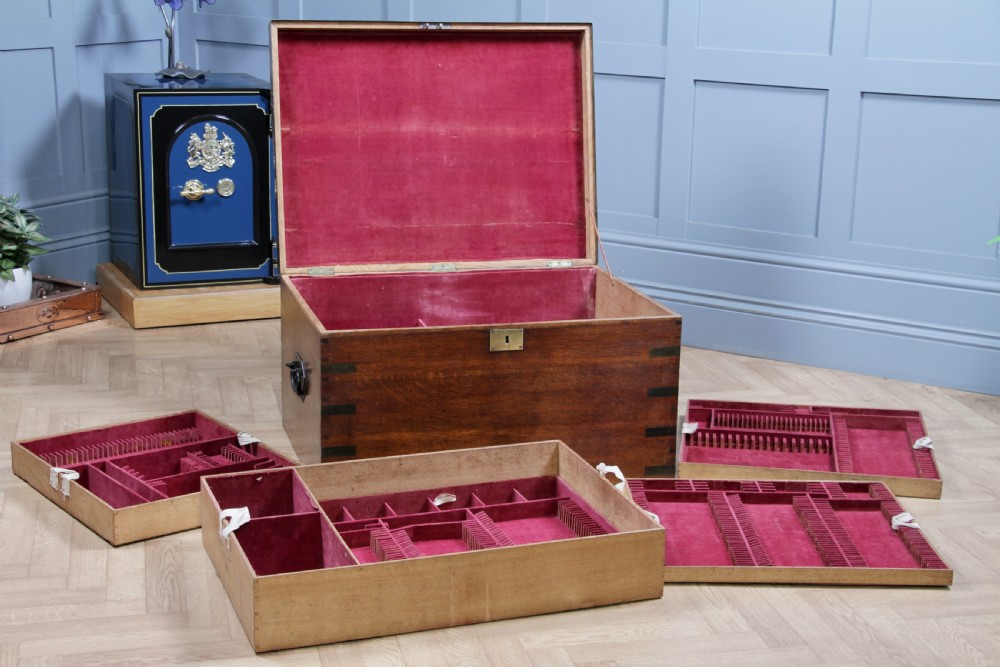 An open Victorian oak campaign trunk featuring brass-bound corners, a central brass keyhole escutcheon, and a fitted interior lined in deep red velvet. View III