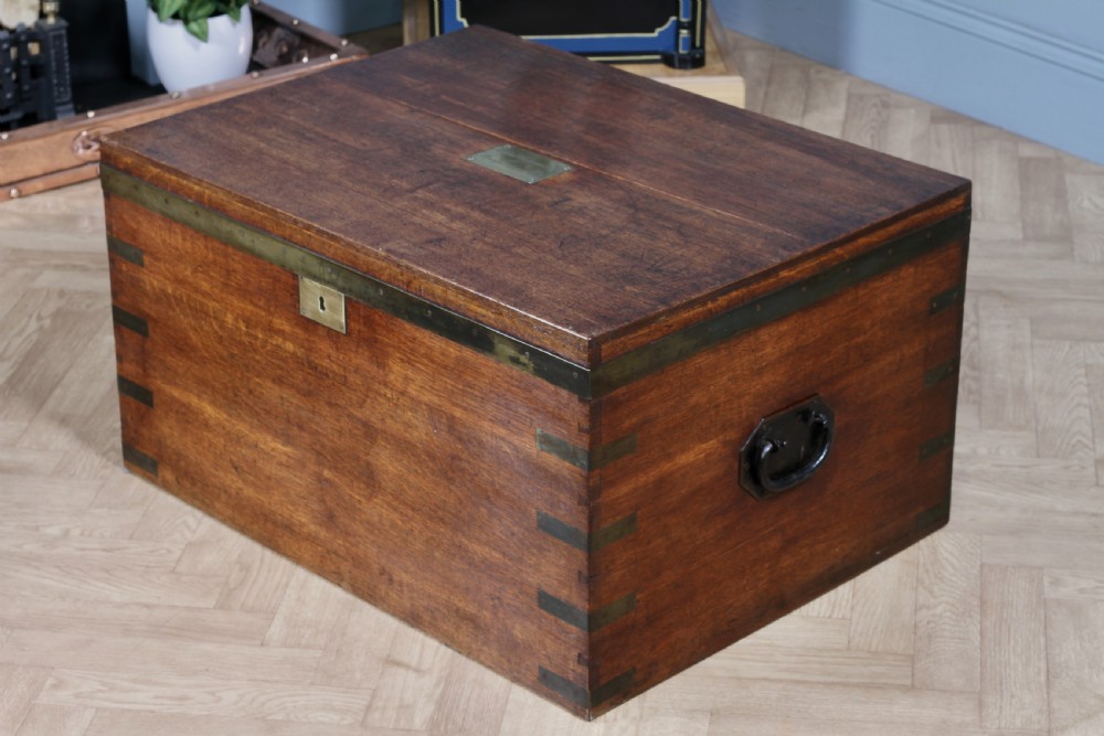 An open Victorian oak campaign trunk featuring brass-bound corners, a central brass keyhole escutcheon, and a fitted interior lined in deep red velvet. View VII