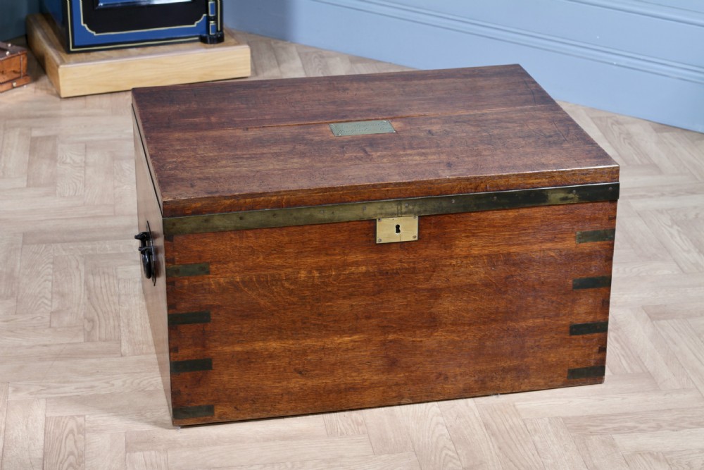 An open Victorian oak campaign trunk featuring brass-bound corners, a central brass keyhole escutcheon, and a fitted interior lined in deep red velvet. View VIII