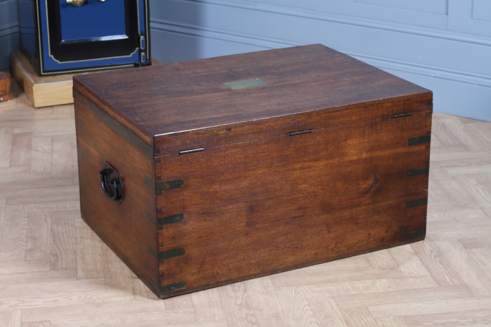 An open Victorian oak campaign trunk featuring brass-bound corners, a central brass keyhole escutcheon, and a fitted interior lined in deep red velvet. View IX