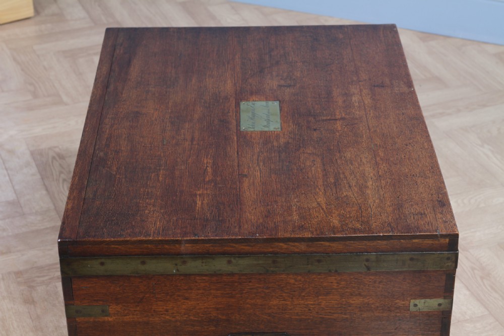 An open Victorian oak campaign trunk featuring brass-bound corners, a central brass keyhole escutcheon, and a fitted interior lined in deep red velvet. View XI