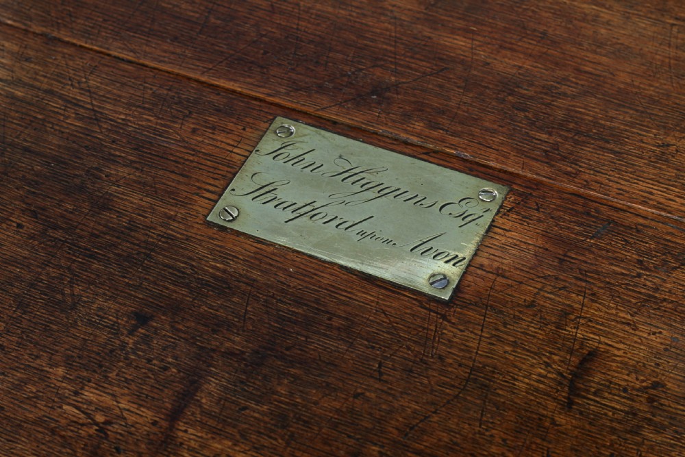 An open Victorian oak campaign trunk featuring brass-bound corners, a central brass keyhole escutcheon, and a fitted interior lined in deep red velvet. View XII
