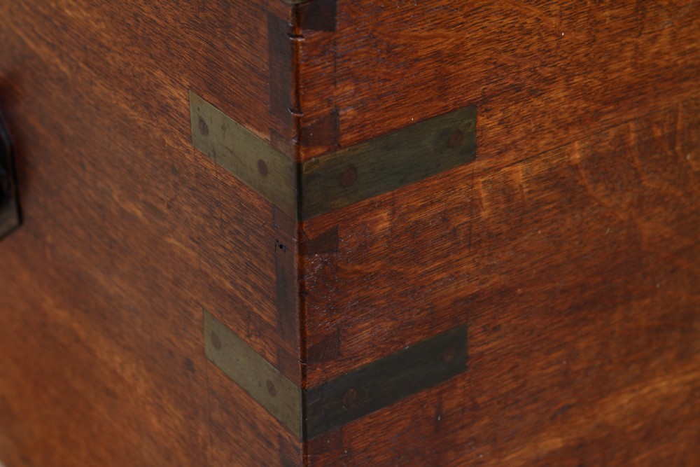 An open Victorian oak campaign trunk featuring brass-bound corners, a central brass keyhole escutcheon, and a fitted interior lined in deep red velvet. View XIV