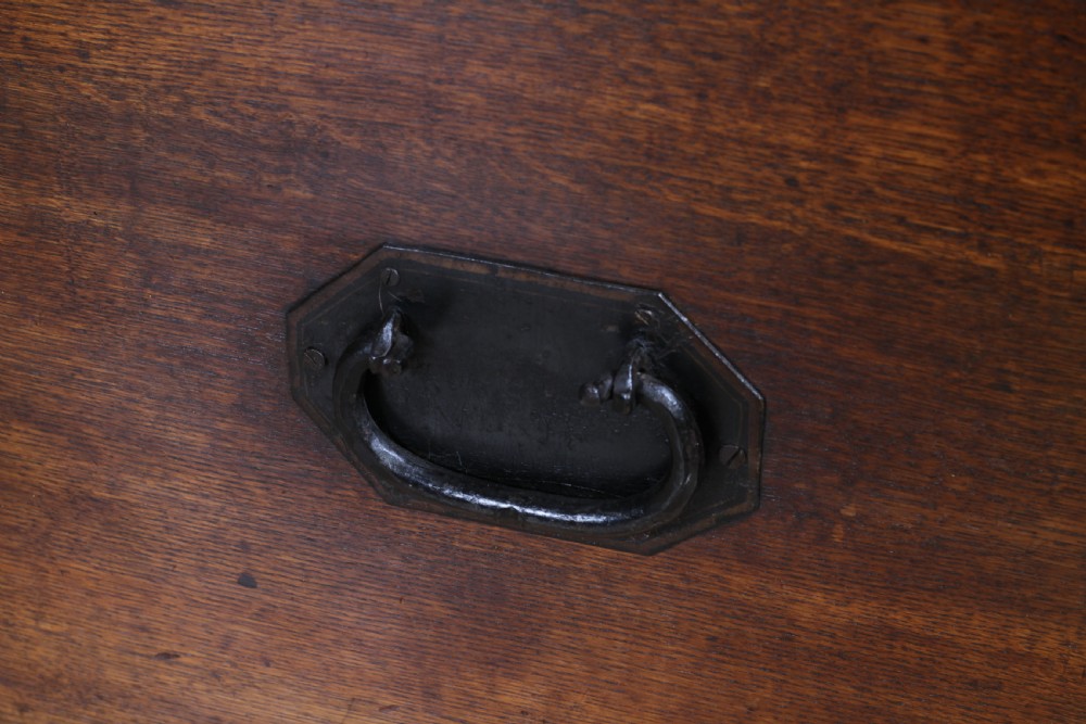 An open Victorian oak campaign trunk featuring brass-bound corners, a central brass keyhole escutcheon, and a fitted interior lined in deep red velvet. View XV