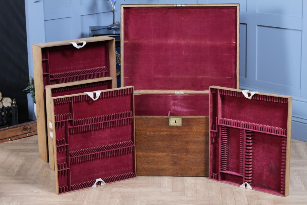 An open Victorian oak campaign trunk featuring brass-bound corners, a central brass keyhole escutcheon, and a fitted interior lined in deep red velvet. View XVI