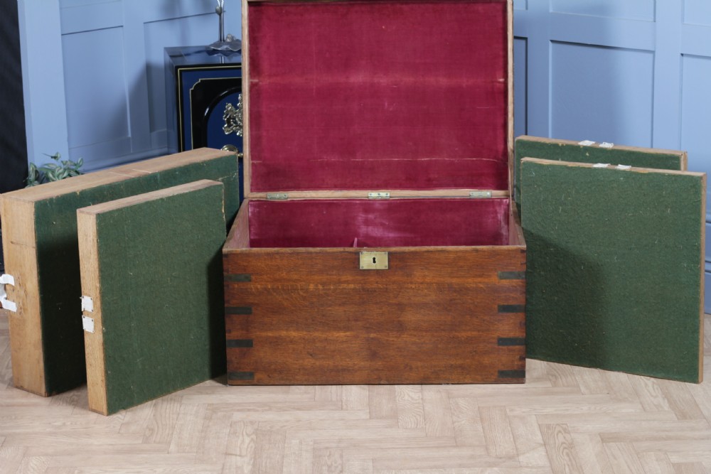 An open Victorian oak campaign trunk featuring brass-bound corners, a central brass keyhole escutcheon, and a fitted interior lined in deep red velvet. View XVII