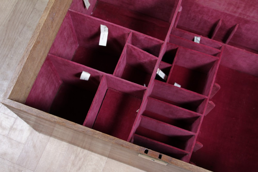 An open Victorian oak campaign trunk featuring brass-bound corners, a central brass keyhole escutcheon, and a fitted interior lined in deep red velvet. View XX