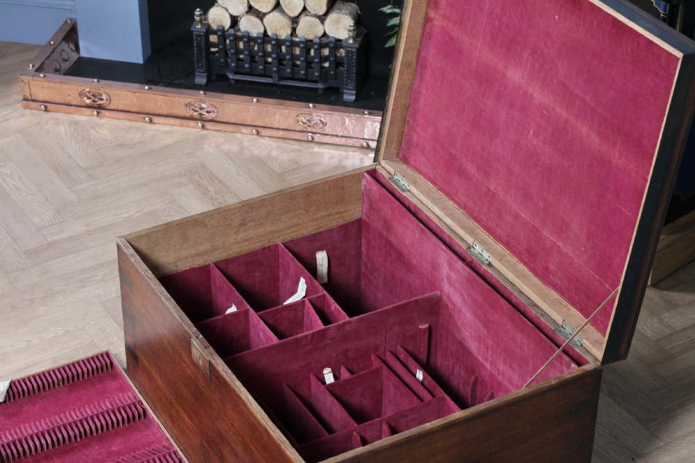 An open Victorian oak campaign trunk featuring brass-bound corners, a central brass keyhole escutcheon, and a fitted interior lined in deep red velvet. View XXII