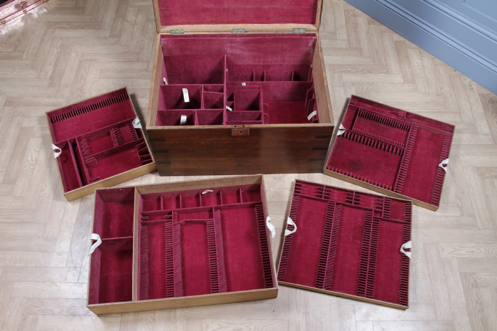 An open Victorian oak campaign trunk featuring brass-bound corners, a central brass keyhole escutcheon, and a fitted interior lined in deep red velvet. View XXIV