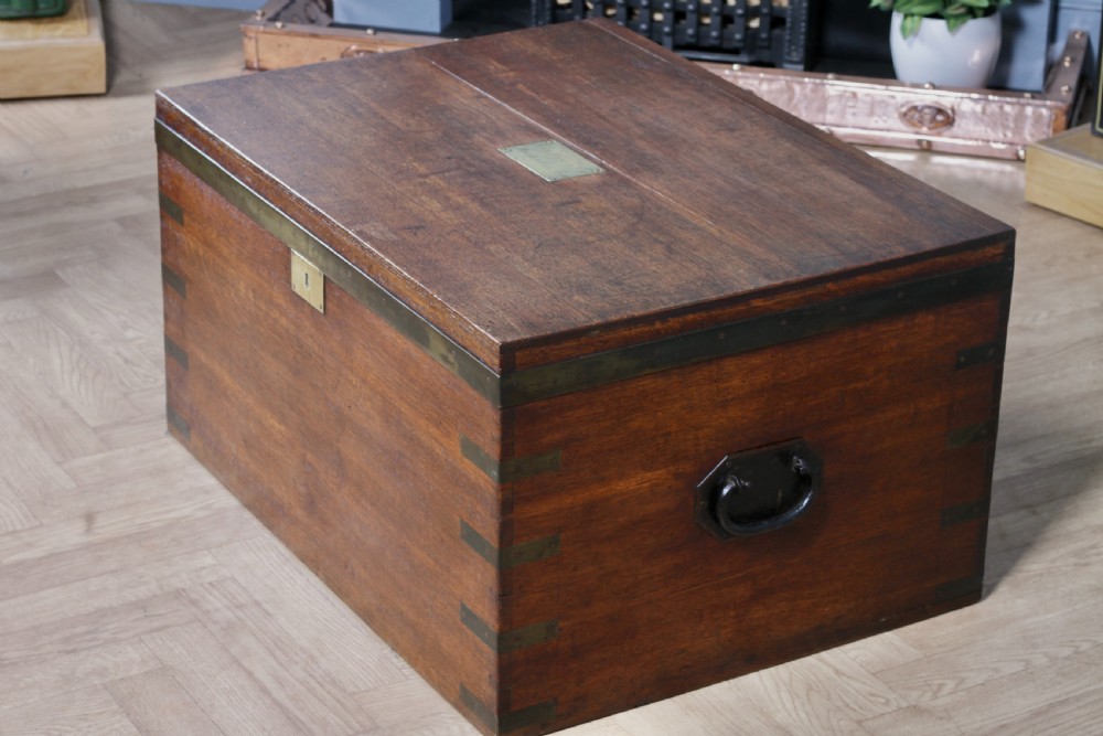 An open Victorian oak campaign trunk featuring brass-bound corners, a central brass keyhole escutcheon, and a fitted interior lined in deep red velvet. View XXV