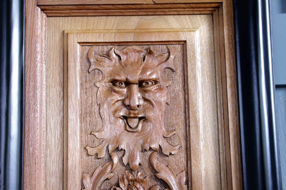 A pair of rectangular carved walnut wall panels featuring detailed grotesque masks and classical urns set within black ebonised frames. View III