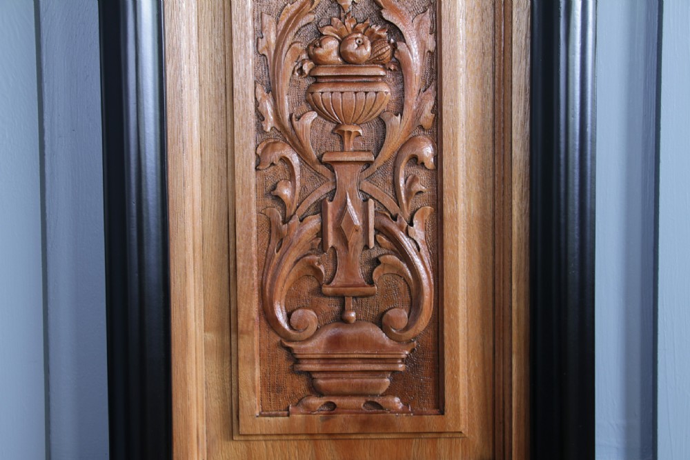 A pair of rectangular carved walnut wall panels featuring detailed grotesque masks and classical urns set within black ebonised frames. View VII