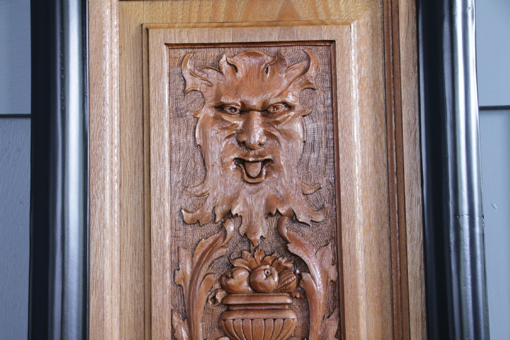 A pair of rectangular carved walnut wall panels featuring detailed grotesque masks and classical urns set within black ebonised frames. View VIII