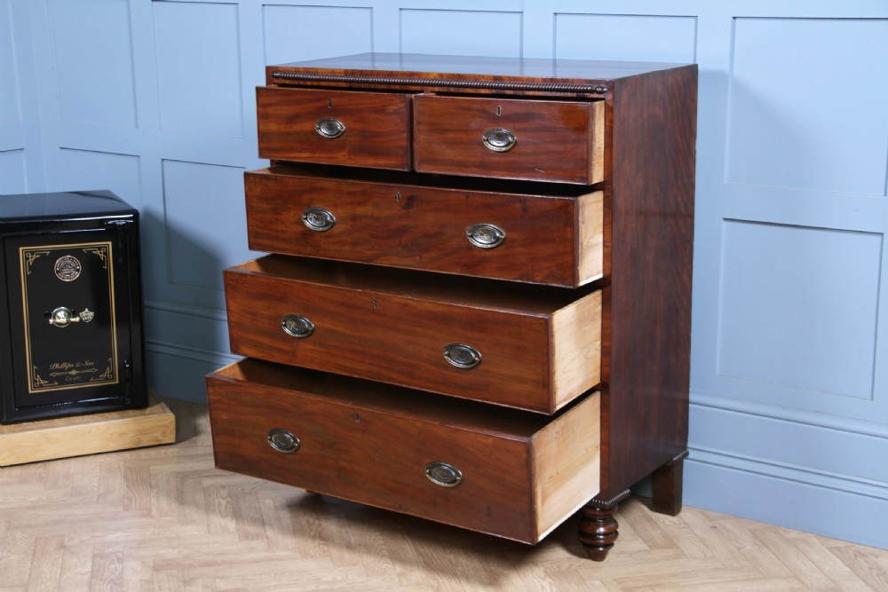 A William IV mahogany chest of drawers featuring two short over three long drawers with oval brass handles and turned feet. View V