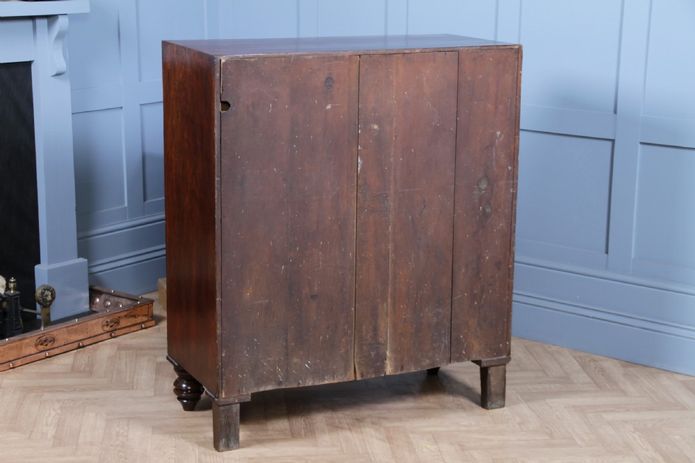 A William IV mahogany chest of drawers featuring two short over three long drawers with oval brass handles and turned feet. View XV