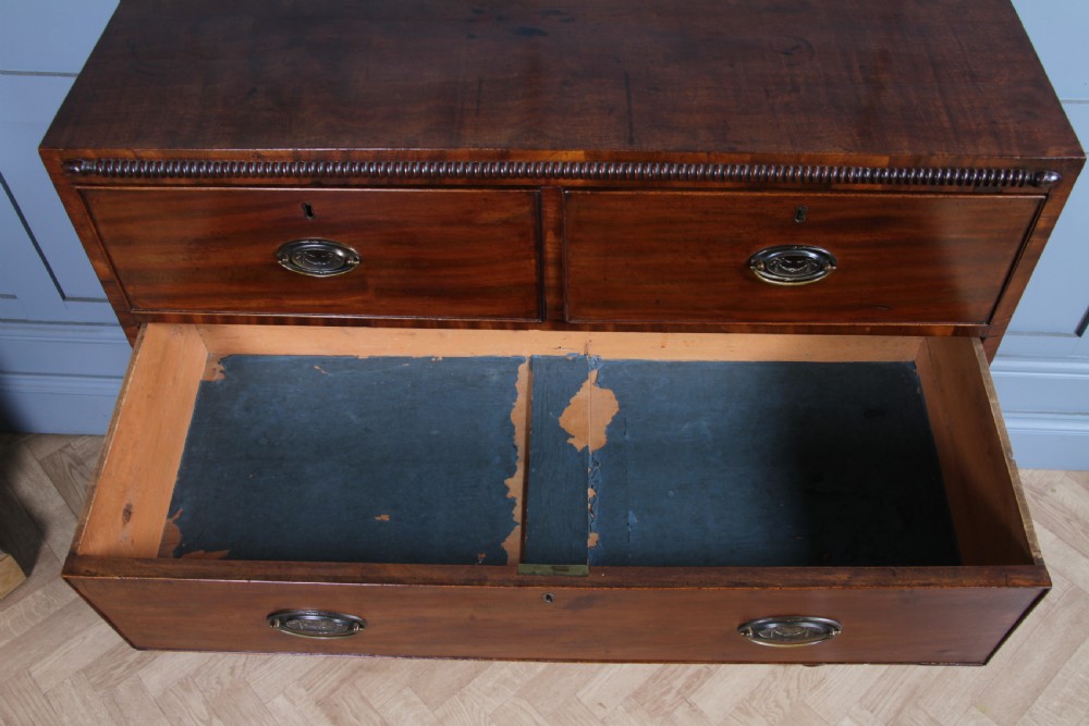 A William IV mahogany chest of drawers featuring two short over three long drawers with oval brass handles and turned feet. View XXII