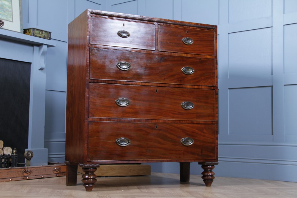 A William IV mahogany chest of drawers featuring two short over three long drawers with oval brass handles and turned feet. View XXIII