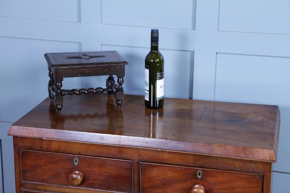 A small dark brown oak miniature stool with relief botanical carving on top, carved side aprons, turned legs, and a central barley twist stretcher. View II