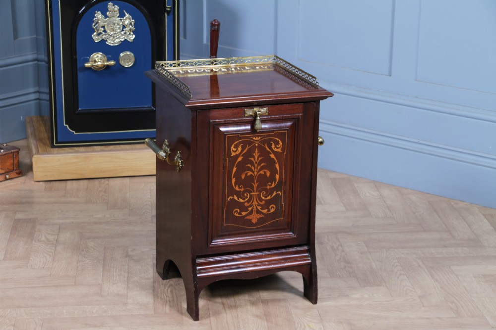 An Edwardian dark mahogany coal purdonium featuring classical floral marquetry inlay, side carry handles, a pierced brass top gallery, and a rear wooden shovel handle.