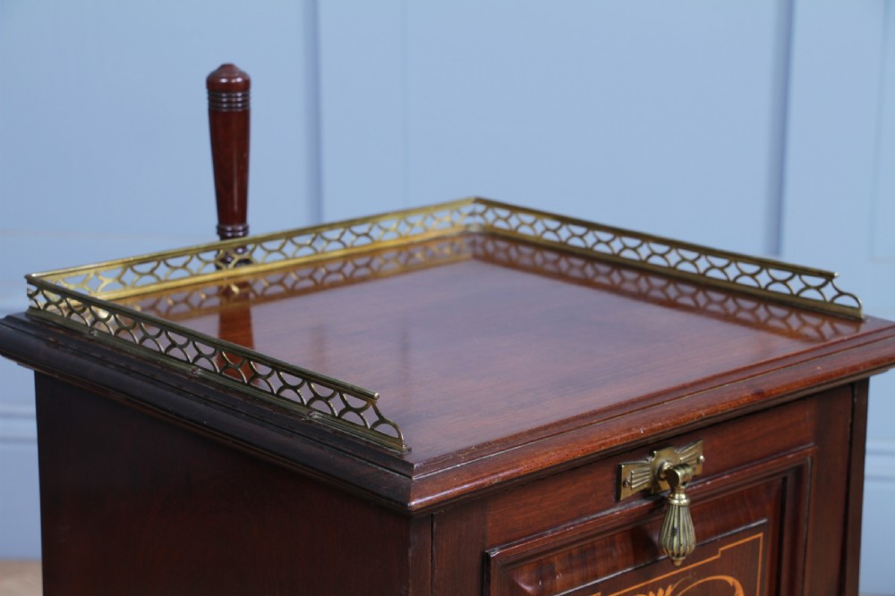 An Edwardian dark mahogany coal purdonium featuring classical floral marquetry inlay, side carry handles, a pierced brass top gallery, and a rear wooden shovel handle. View X