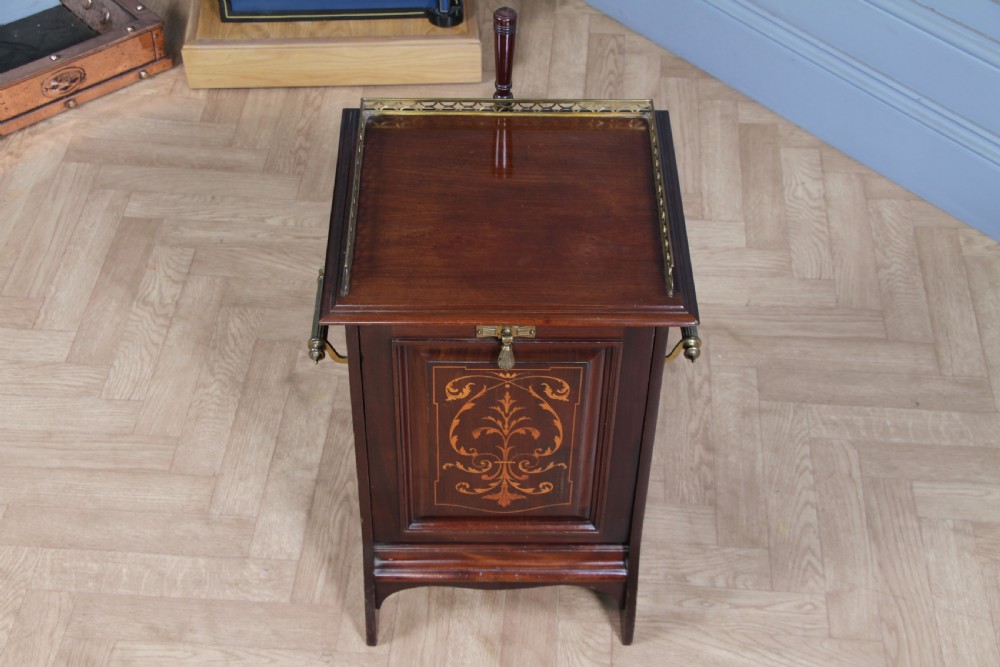 An Edwardian dark mahogany coal purdonium featuring classical floral marquetry inlay, side carry handles, a pierced brass top gallery, and a rear wooden shovel handle. View XII