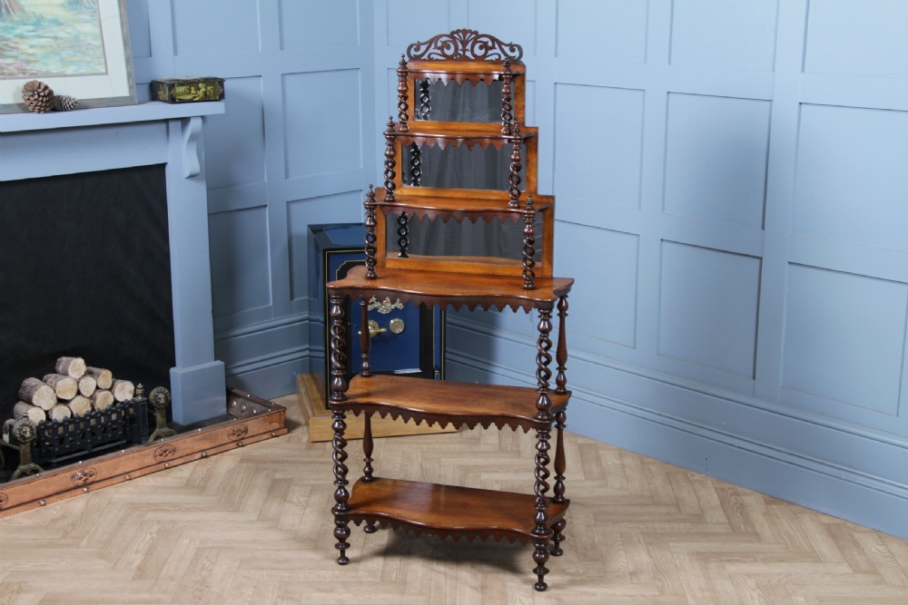 A Victorian six-tier walnut whatnot display shelf featuring hollow barley twist columns, mirrored back panels, and carved fretwork cresting.