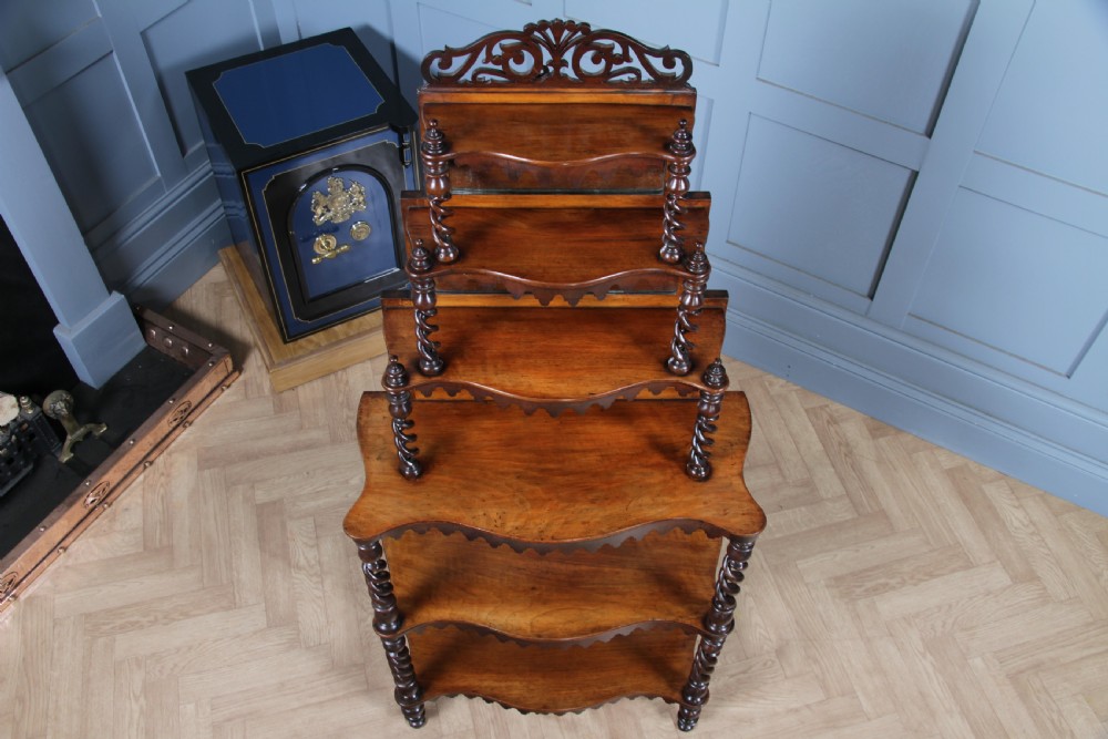 A Victorian six-tier walnut whatnot display shelf featuring hollow barley twist columns, mirrored back panels, and carved fretwork cresting. View II