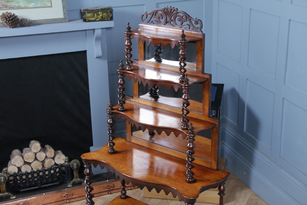 A Victorian six-tier walnut whatnot display shelf featuring hollow barley twist columns, mirrored back panels, and carved fretwork cresting. View V