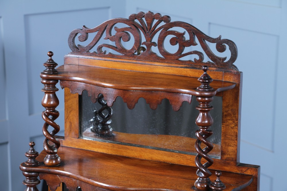 A Victorian six-tier walnut whatnot display shelf featuring hollow barley twist columns, mirrored back panels, and carved fretwork cresting. View VI