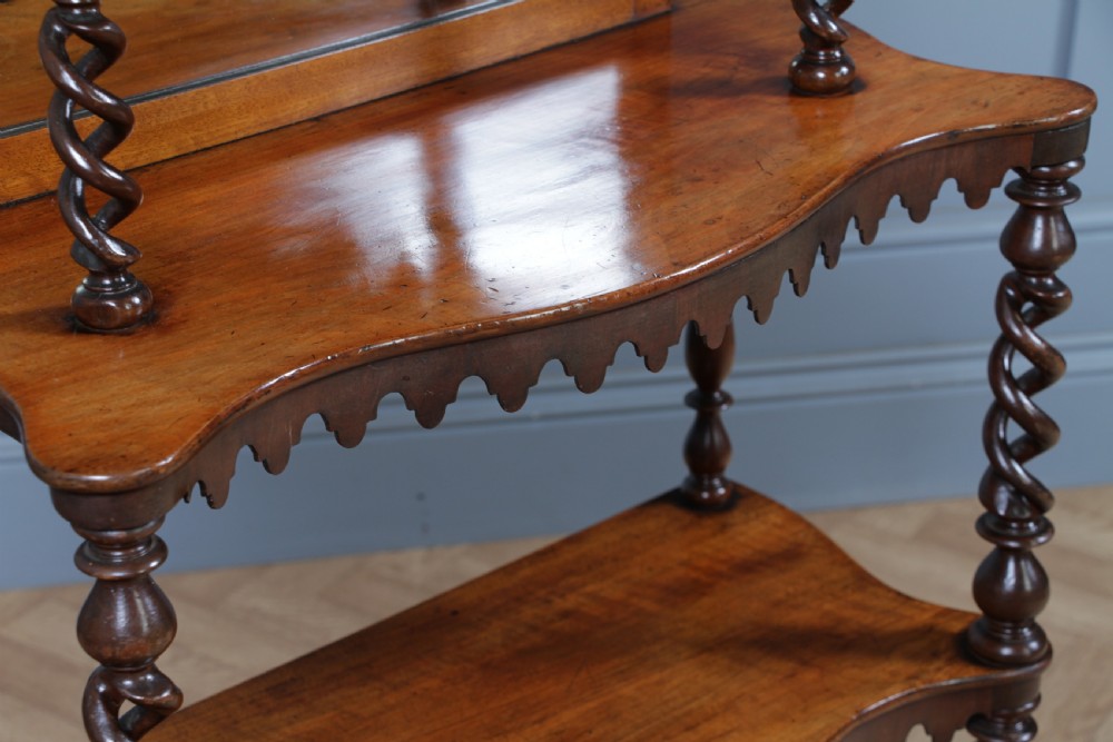 A Victorian six-tier walnut whatnot display shelf featuring hollow barley twist columns, mirrored back panels, and carved fretwork cresting. View XII