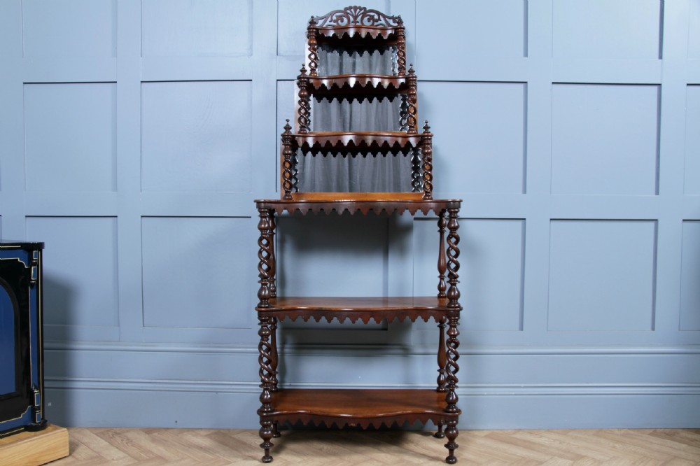 A Victorian six-tier walnut whatnot display shelf featuring hollow barley twist columns, mirrored back panels, and carved fretwork cresting. View XV
