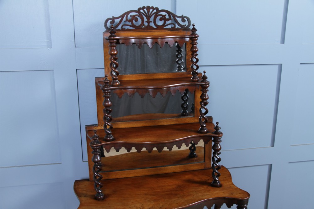 A Victorian six-tier walnut whatnot display shelf featuring hollow barley twist columns, mirrored back panels, and carved fretwork cresting. View XVI